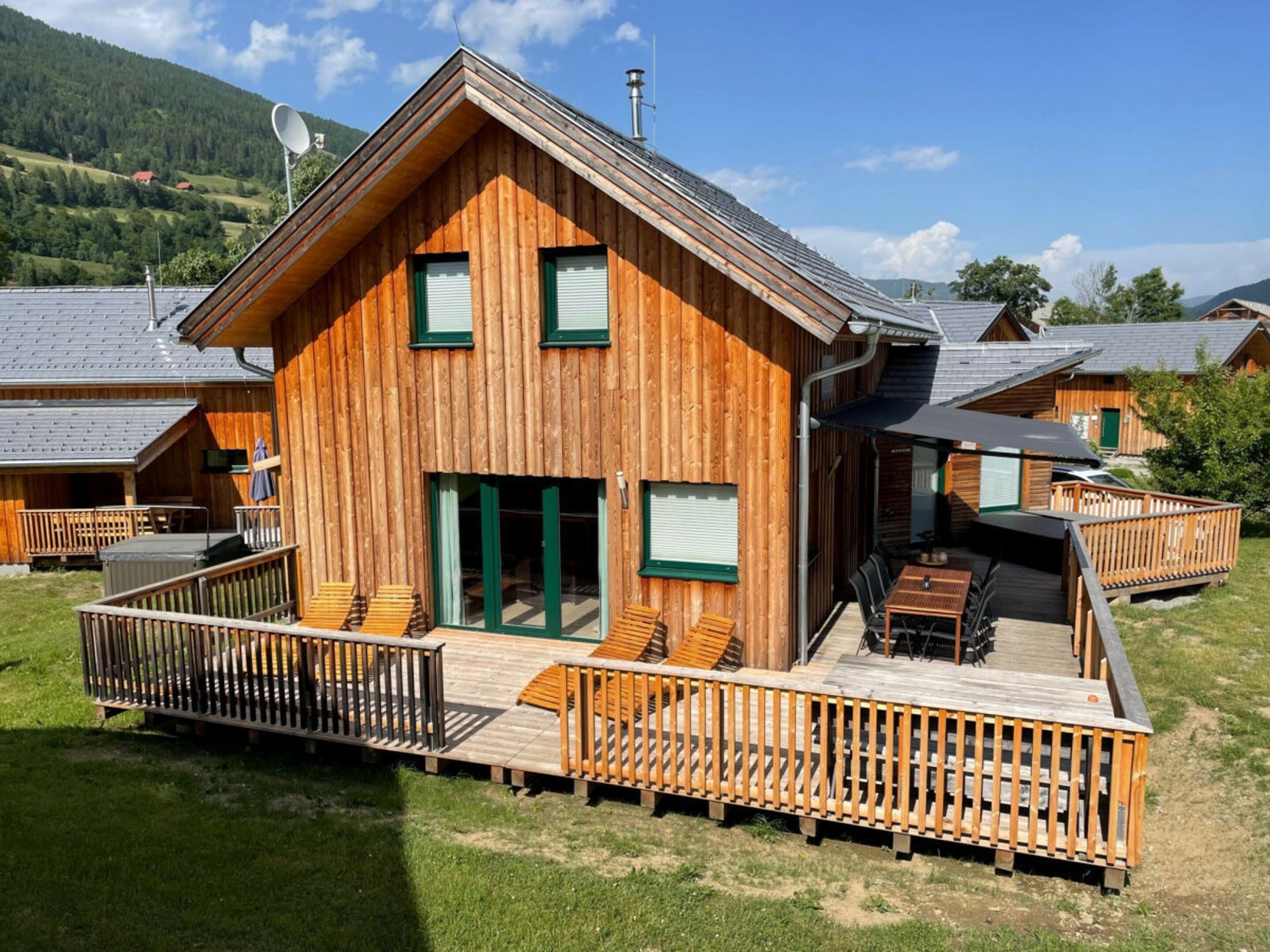 Une cabane en bois dotée d’une terrasse, de meubles de jardin et offrant une vue sur le paysage environnant.