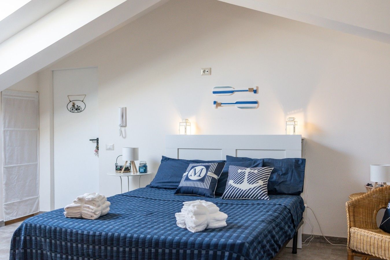 Ein Schlafzimmer mit einem Bett, Kissen, einem Nachttisch, einer Lampe und einer Wandleuchte.