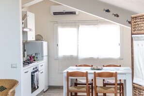 Ett kompakt kök med ett matbord, stolar och ett fönster med gardiner.
