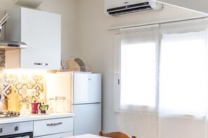 Eine kleine Küche mit Kühlschrank, Herd und einem Fenster mit Vorhängen.
