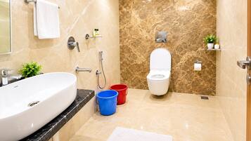 A modern bathroom with a large white sink, a toilet, and a shower area.