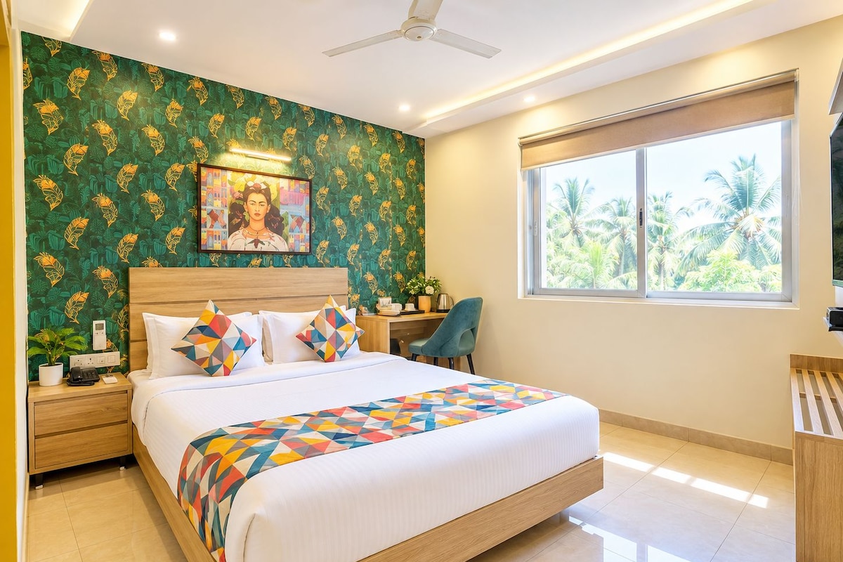 A modern bedroom with a large bed, a desk, and a window with a view of palm trees.