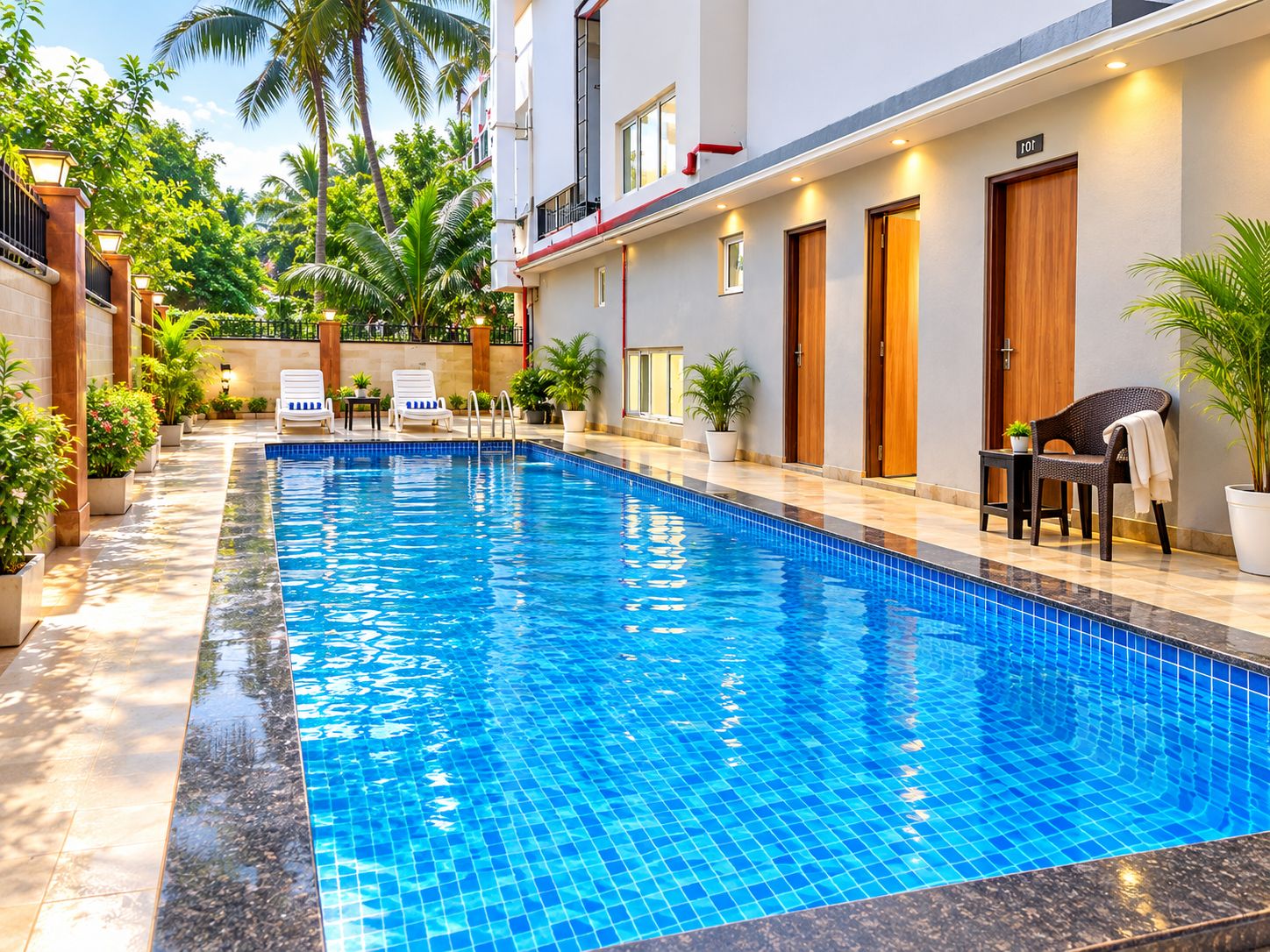 A swimming pool with a tiled edge, surrounded by potted plants and outdoor seating.