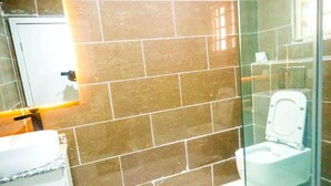 Un bagno con una cabina doccia in vetro, un WC bianco e un lavabo con piano in marmo.