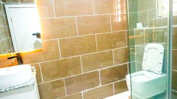 A bathroom with a glass partition, a white toilet, and a sink with a marble countertop.