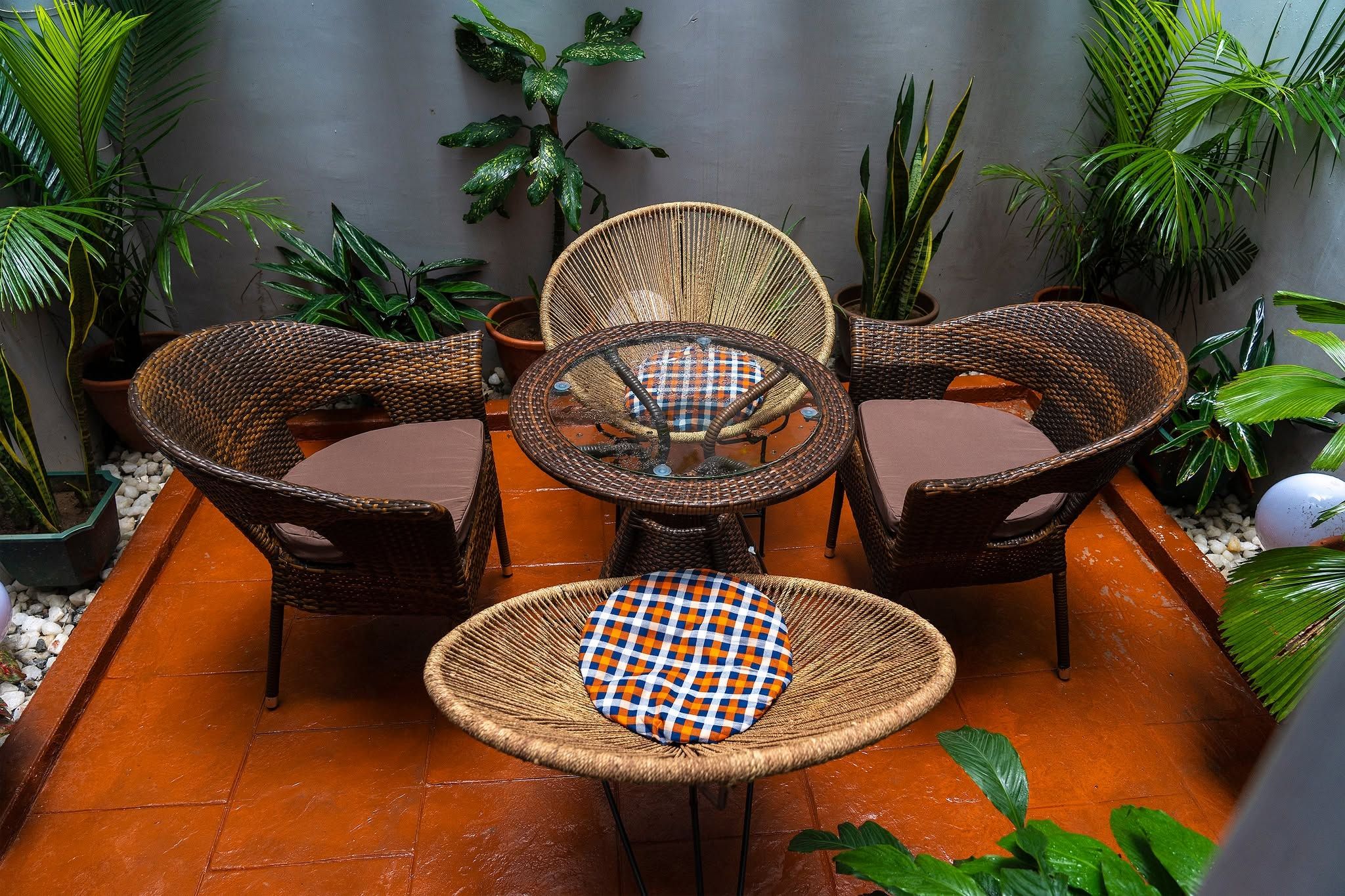 A patio with wicker furniture, including a table and chairs, surrounded by potted plants.