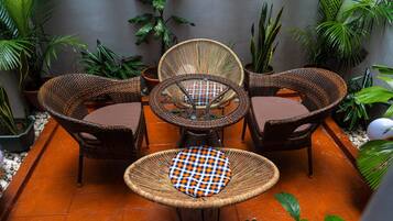 A patio with wicker furniture, including a table and chairs, surrounded by potted plants.