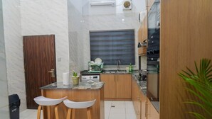 Una cucina compatta con piano di lavoro in marmo, mobili in legno, piano cottura integrato e una piccola isola con sgabelli.