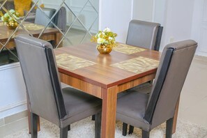 Una mesa de comedor con cuatro sillas, un florero con flores y un mantel decorado.