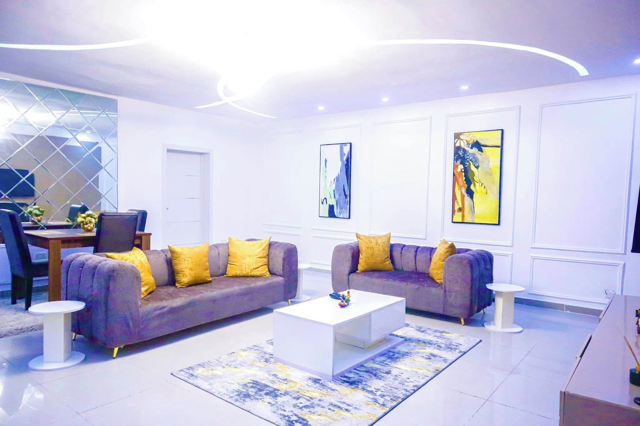 Una sala de estar moderna con dos sofás, una mesa de centro y obras de arte en las paredes.