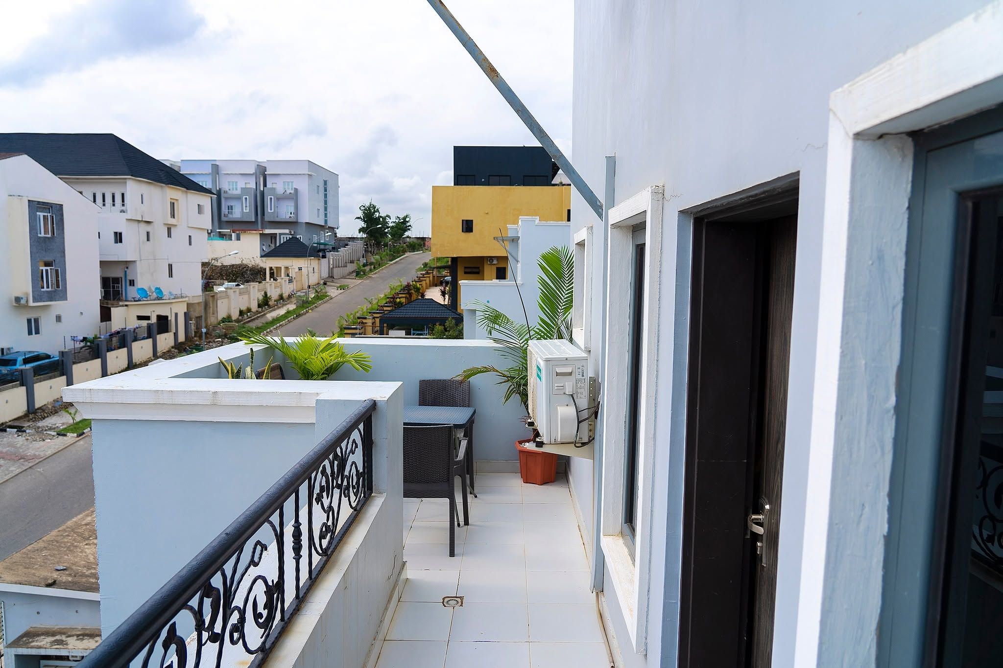 A balcony with a table and chairs, a potted plant, and a door.