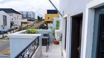 A balcony with a table and chairs, a potted plant, and a door.