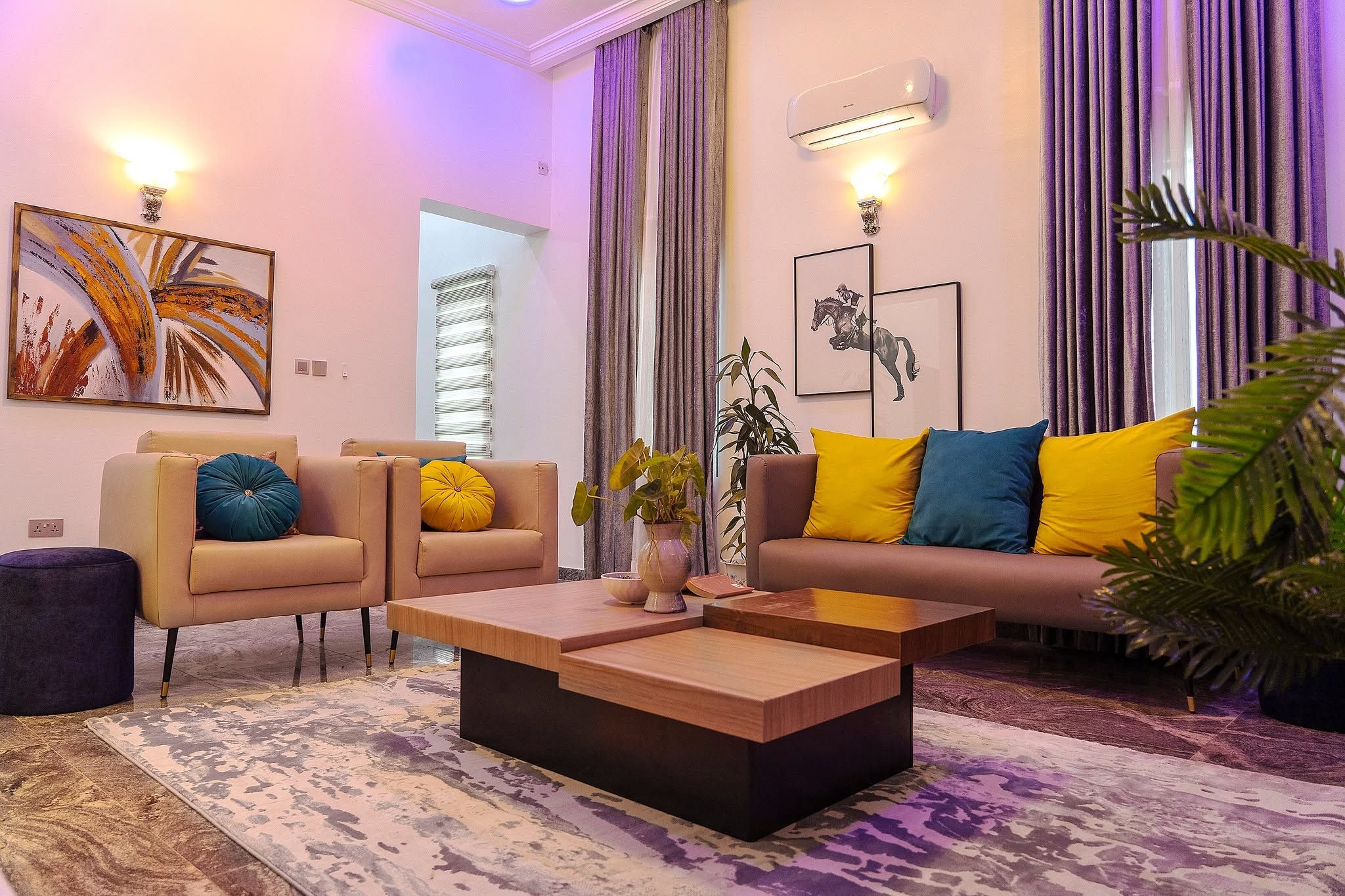 A modern living room with a sofa, two armchairs, a coffee table, and a potted plant.