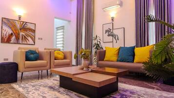A modern living room with a sofa, two armchairs, a coffee table, and a potted plant.