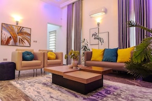 A modern living room with a sofa, two armchairs, a coffee table, and a potted plant. - Ken Kol Apartment  (Lekki)