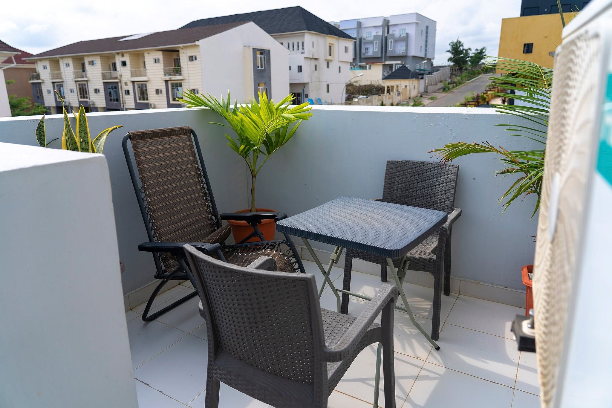 A balcony with two chairs, a table, and a potted plant.