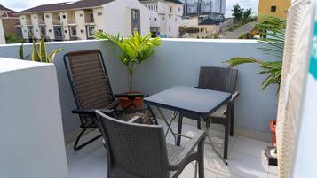 A balcony with two chairs, a table, and a potted plant.