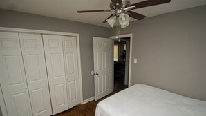 Un dormitorio con cama, ventilador de techo y puertas dobles blancas.