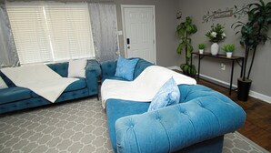 Un salón con un sofá azul, una puerta blanca y una estantería con plantas.