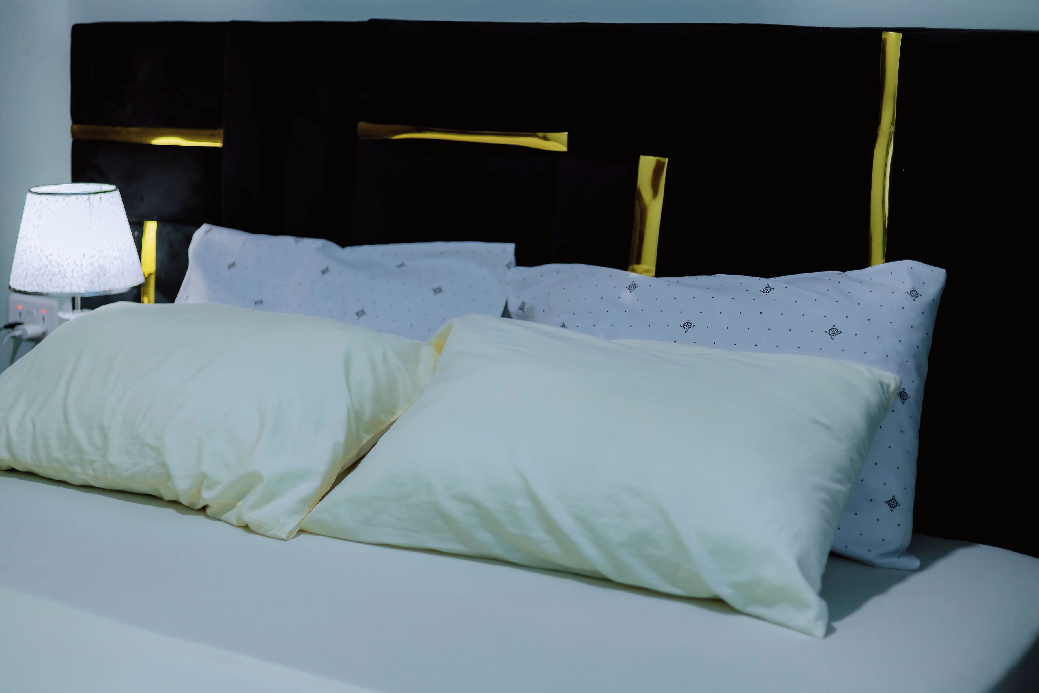 Una cama con ropa blanca y una lámpara en una mesita de noche.