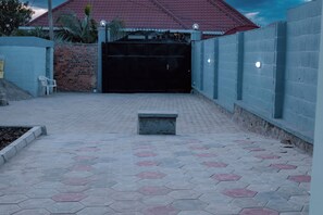 Un patio empedrado con un banco, un muro de ladrillo y una verja.