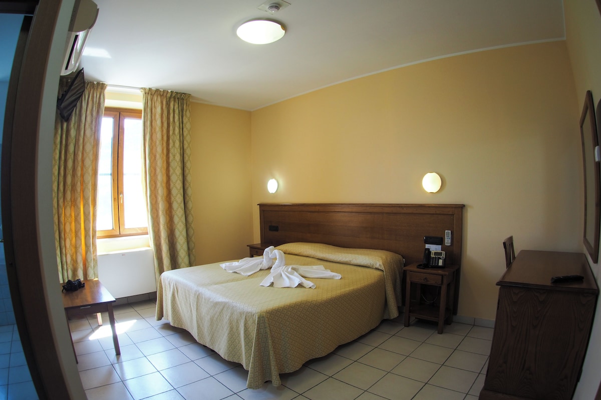 Una habitació d'hotel amb un llit, una taula de nit i una petita taula amb un telèfon.