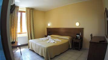 Una camera d'albergo con un letto, un comodino e un tavolino con il telefono.