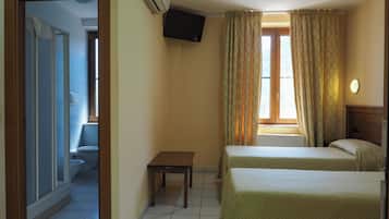 A hotel room with two beds, a television mounted on the wall, and a bathroom visible through an open door.