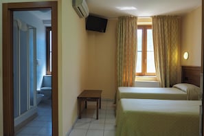 A hotel room with two beds, a television mounted on the wall, and a bathroom visible through an open door. - Hotel Ristorante da Santina (Castro dei Volsci)
