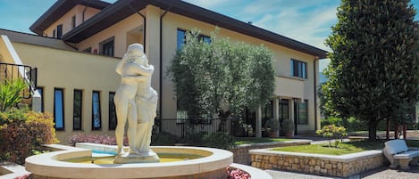 A courtyard with a central fountain, a statue, and a building with a balcony.