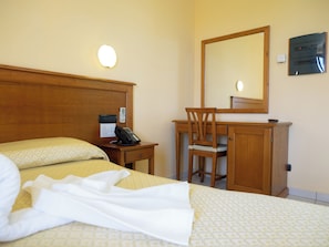 A hotel room with a bed, a desk, a chair, a telephone, a mirror, and a wall-mounted electrical panel. - Hotel Ristorante da Santina (Castro dei Volsci)