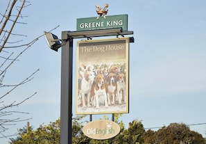 A sign for 'The Dog House' pub with a dog illustration and the name 'Greene King' above it.