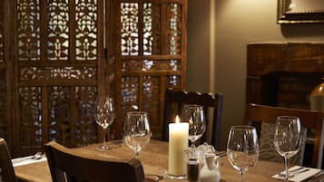 Una mesa de comedor con copas de vino, una vela y saleros y pimenteros.