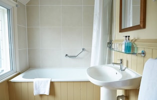 A bathroom with a bathtub, a sink, and a shower area.