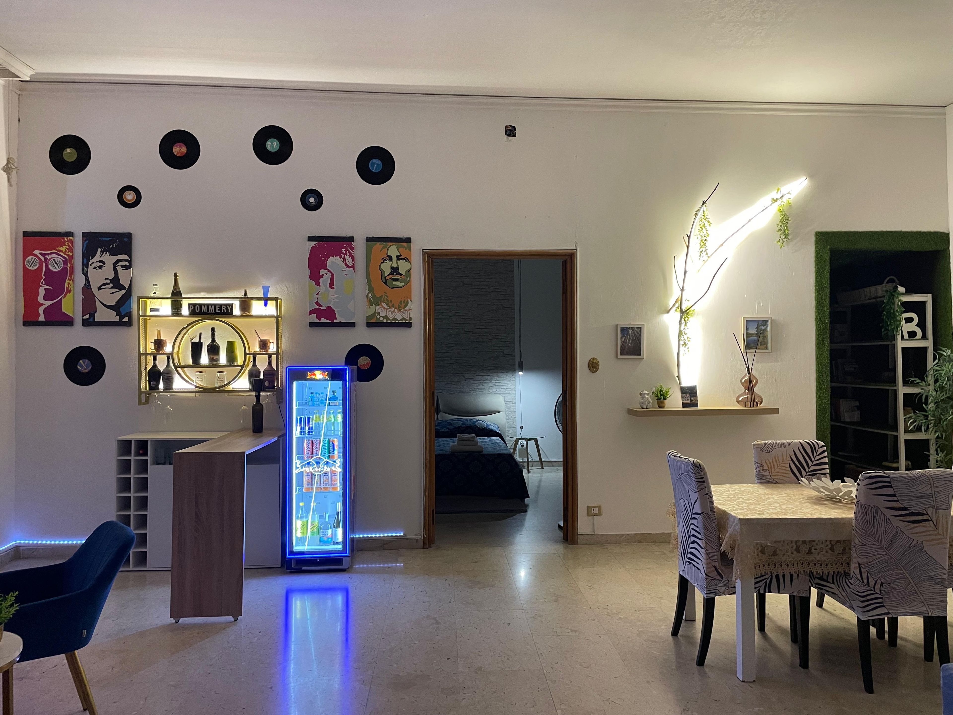 A modern living room with a bar area, a dining table, and a kitchen in the background.