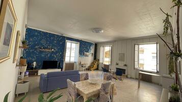 Un salon avec un mur bleu, un canapé, une table à manger avec des chaises et une cheminée.
