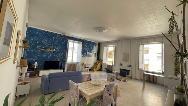 A living room with a blue wall, a sofa, a dining table with chairs, and a fireplace. - Vrbo Property (Lamezia Terme)
