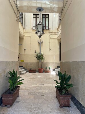 A corridor with a central staircase, potted plants, and a hanging light fixture.