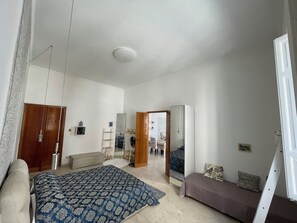 A bedroom with a bed, a sofa, a wardrobe, and a mirror.