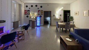 A modern living room with a blue sofa, a coffee table, a dining area with a table and chairs, a refrigerator, and a kitchen area in the background. - Vrbo Property (Lamezia Terme)