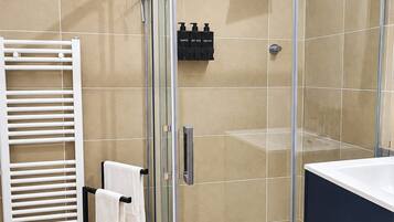A modern bathroom with a glass-enclosed shower, a white towel rack, and a black cabinet.