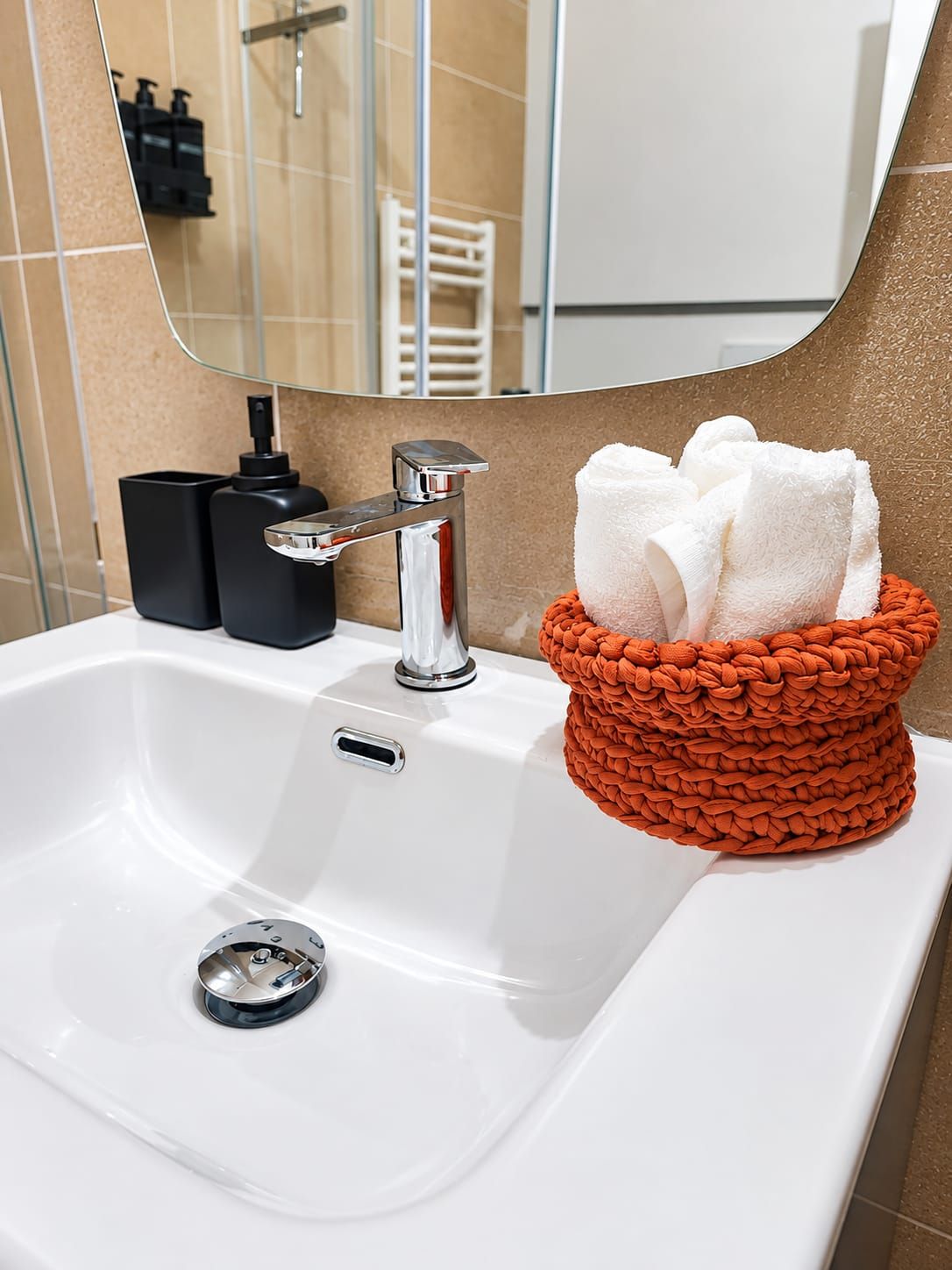 Un lavabo con rubinetteria cromata, un erogatore di sapone e un portaservizi con asciugamani bianchi.