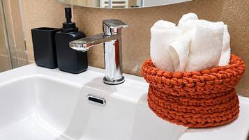 Un lavabo con rubinetteria cromata, un erogatore di sapone e un portaservizi con asciugamani bianchi.