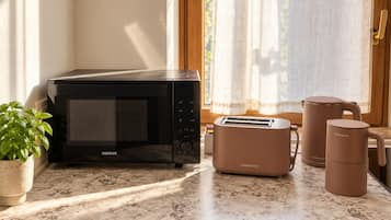 Una cocina con microondas, tostadora y dos cafeteras sobre una encimera de mármol.