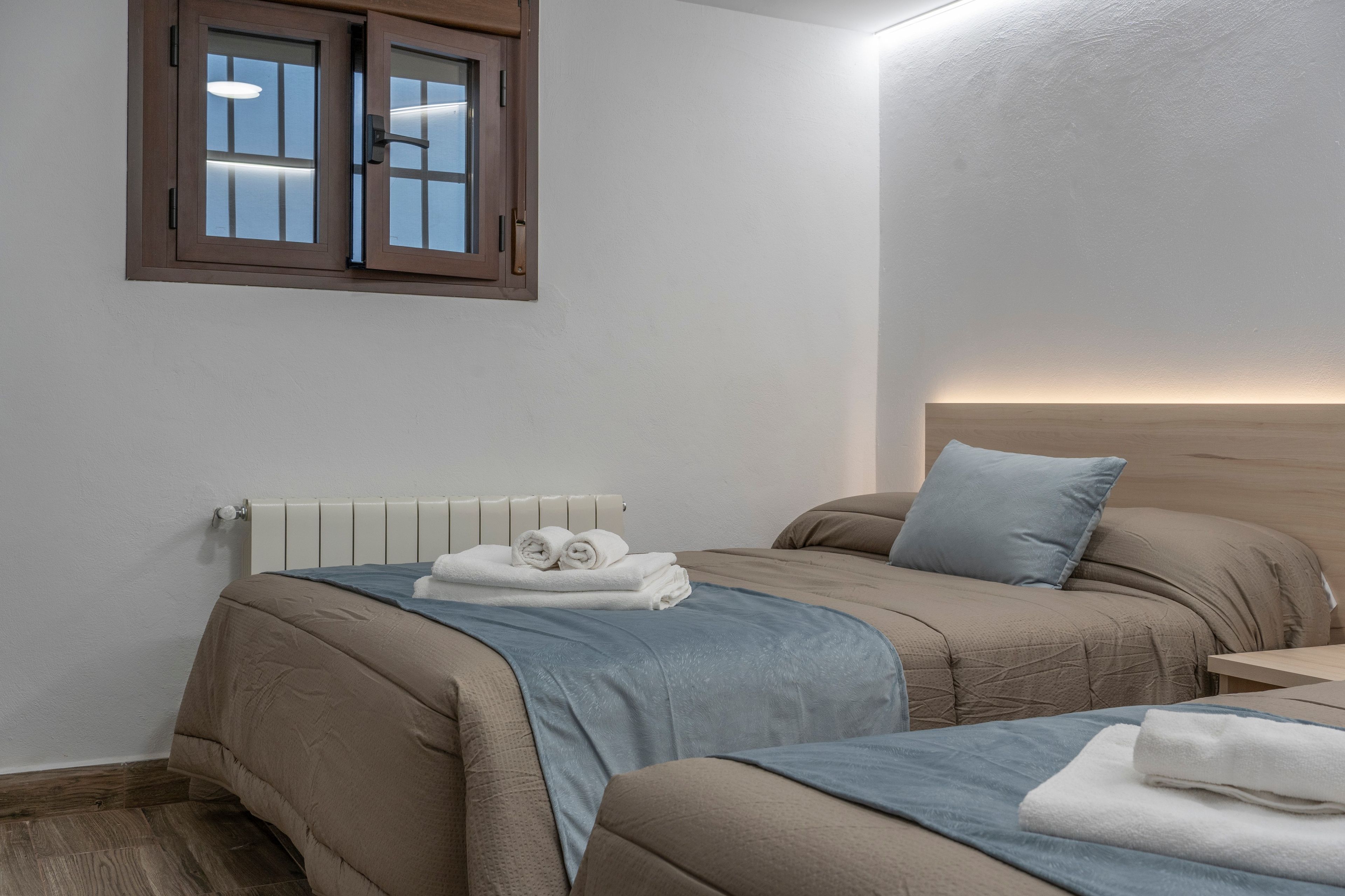 Habitación de hotel con dos camas, un radiador y una ventana con vistas.