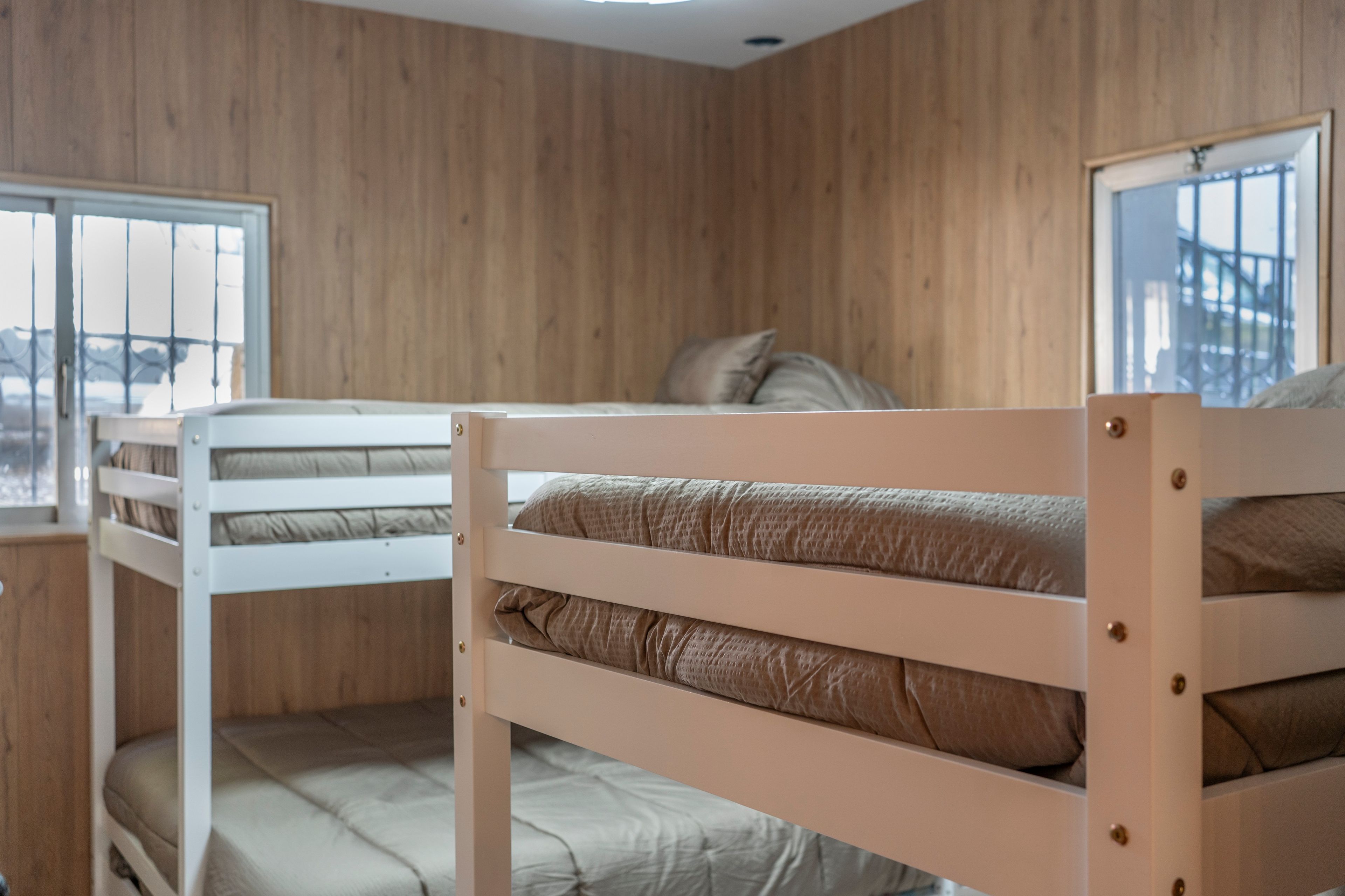 Une chambre avec un lit superposé, des murs en bois et une fenêtre.