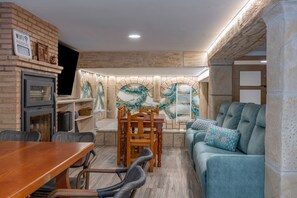 A cozy living room with a fireplace, a dining area, and a sofa with patterned cushions.