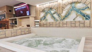 A spa area with a hot tub, a television displaying 'SPEEDVISION', and a decorative wall with a marble-like pattern.