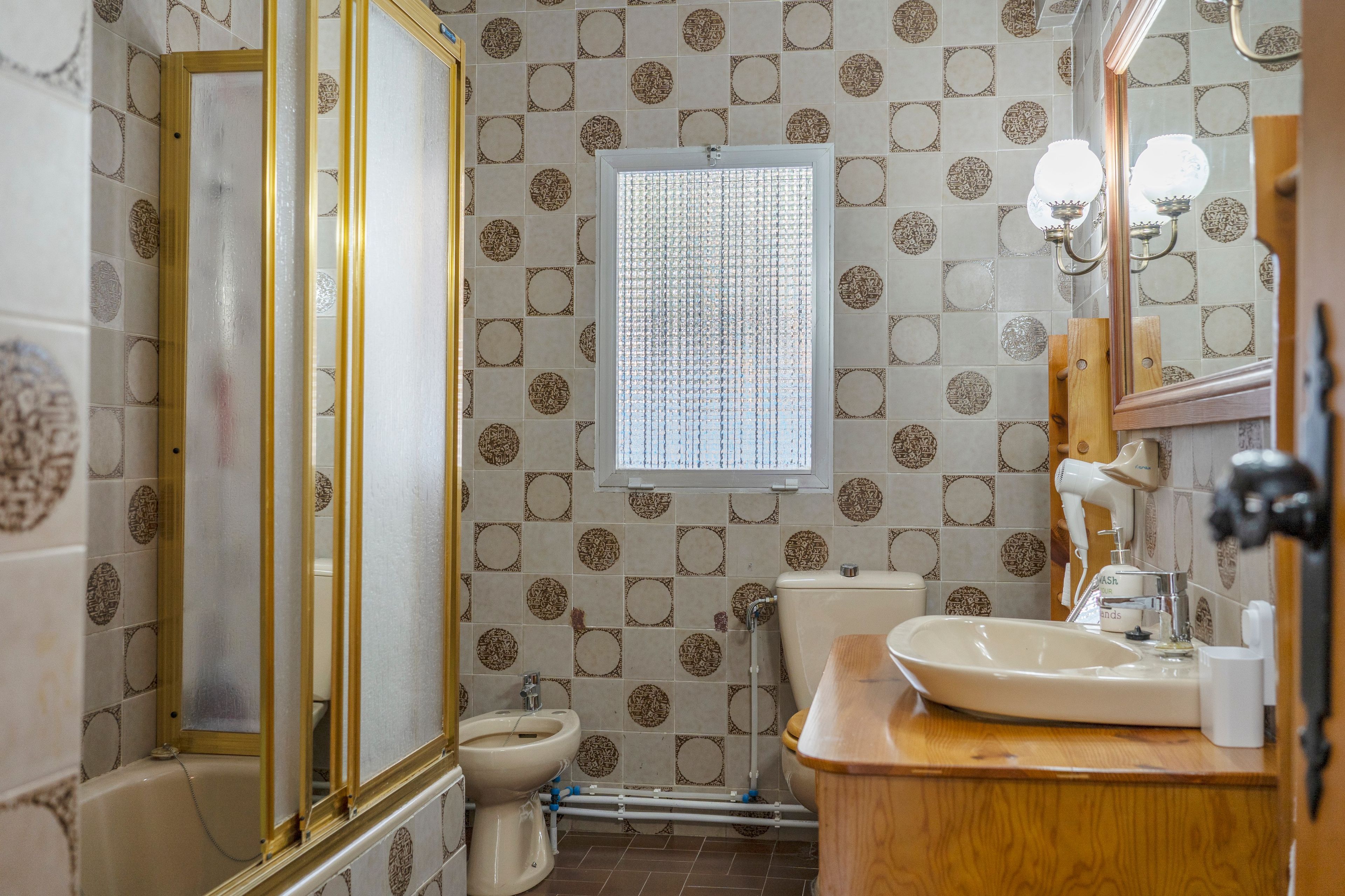 Une salle de bain comprenant des toilettes, un bidet, un lavabo et un miroir.