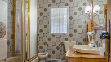 Une salle de bain comprenant des toilettes, un bidet, un lavabo et un miroir.